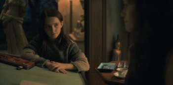 Movie still from “The Haunting of Hill House” (2018), directed by Mike Flanagan – A young girl sitting at a table in front of an older man; Close Up shot, Over the shoulder angle