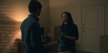 Movie still from “The Haunting of Hill House” (2018), directed by Mike Flanagan – Two people standing in front of boxes in a room; Medium shot, Over the shoulder angle