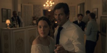 Movie still from “The Haunting of Hill House” (2018), directed by Mike Flanagan – A man and a woman pose for a picture; Medium shot, Over the shoulder angle