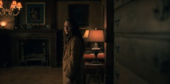 Movie still from “The Haunting of Hill House” (2018), directed by Mike Flanagan – A woman standing in a dark room with a lamp; Medium shot, High angle