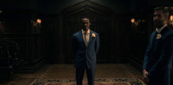 Movie still from “The Haunting of Hill House” (2018), directed by Mike Flanagan – A man wearing a suit and tie standing in a room; Wide shot, Low angle