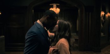 Movie still from “The Haunting of Hill House” (2018), directed by Mike Flanagan – A man and a woman kissing each other in front of a chandelier; Medium shot, Low angle