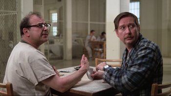 Movie still from “One Flew Over the Cuckoo's Nest” (1975), directed by Milos Forman – Two men sitting at a table in front of each other; Close Up shot, Over the shoulder angle