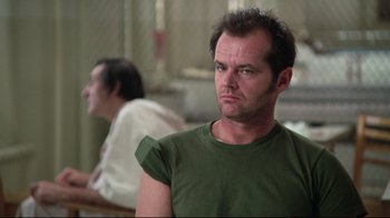 Movie still from “One Flew Over the Cuckoo's Nest” (1975), directed by Milos Forman – A man in a green t - shirt is looking to his left; Close Up shot, Low angle
