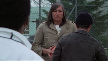 Movie still from “One Flew Over the Cuckoo's Nest” (1975), directed by Milos Forman – A man with long black hair talking to two other men; Medium shot, Over the shoulder angle