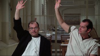 Movie still from “One Flew Over the Cuckoo's Nest” (1975), directed by Milos Forman – Two people raising their hands in the air in front of a priest; Medium shot, Low angle