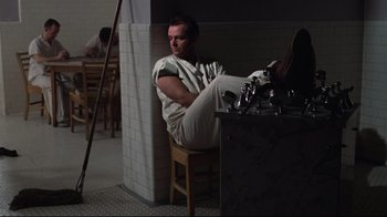 Movie still from “One Flew Over the Cuckoo's Nest” (1975), directed by Milos Forman – A man sitting on top of a wooden chair; Wide shot, Low angle