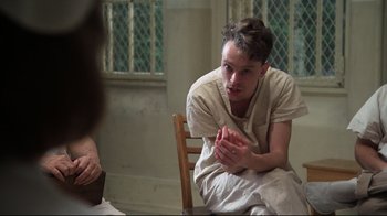 Movie still from “One Flew Over the Cuckoo's Nest” (1975), directed by Milos Forman – A man sitting on a chair in front of a window; Medium shot, Over the shoulder angle