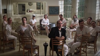 Movie still from “One Flew Over the Cuckoo's Nest” (1975), directed by Milos Forman – A group of people sitting in chairs in a room; Wide shot, High angle
