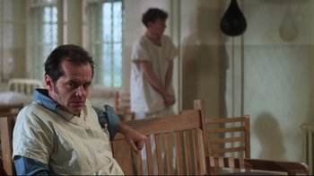 Movie still from “One Flew Over the Cuckoo's Nest” (1975), directed by Milos Forman – A man sitting on a wooden bench in front of another man; Medium shot, Low angle