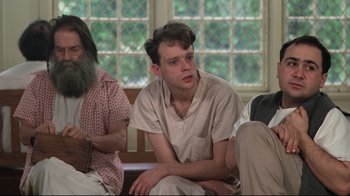 Movie still from “One Flew Over the Cuckoo's Nest” (1975), directed by Milos Forman – A man sitting on a couch next to two other men; Medium shot, Low angle