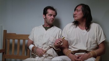 Movie still from “One Flew Over the Cuckoo's Nest” (1975), directed by Milos Forman – A couple of men sitting next to each other on top of a bench; Medium shot, Low angle