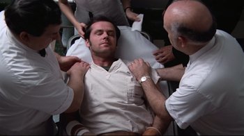 Movie still from “One Flew Over the Cuckoo's Nest” (1975), directed by Milos Forman – A man is being examined by two doctors; Medium shot, Low angle