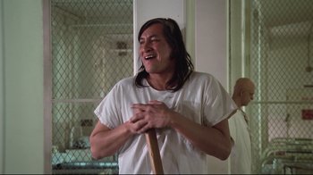 Movie still from “One Flew Over the Cuckoo's Nest” (1975), directed by Milos Forman – A man with long hair holding a baseball bat in his hands; Medium shot, Low angle