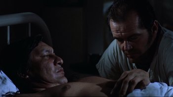 Movie still from “One Flew Over the Cuckoo's Nest” (1975), directed by Milos Forman – A man looking at another man in a dark room; Medium shot, Low angle