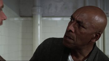 Movie still from “One Flew Over the Cuckoo's Nest” (1975), directed by Milos Forman – An older man sitting in front of a brick wall; Close Up shot, Over the shoulder angle