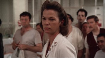 Movie still from “One Flew Over the Cuckoo's Nest” (1975), directed by Milos Forman – A group of people standing in a room with a woman in a white lab coat; Close Up shot, Low angle