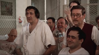 Movie still from “One Flew Over the Cuckoo's Nest” (1975), directed by Milos Forman – A group of men in white shirts and one man holding a microphone; Medium shot, Low angle