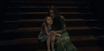 Movie still from “The Haunting of Hill House” (2018), directed by Mike Flanagan – A woman sitting on the stairs with a little girl; Medium shot, High angle