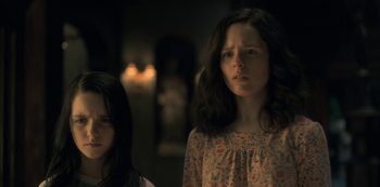 Movie still from “The Haunting of Hill House” (2018), directed by Mike Flanagan – Two young girls standing next to each other in a dark room; Close Up shot, Low angle