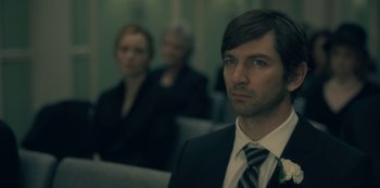 Movie still from “The Haunting of Hill House” (2018), directed by Mike Flanagan – A man wearing a suit and tie in front of two other people; Close Up shot, Over the shoulder angle