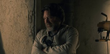 Movie still from “The Haunting of Hill House” (2018), directed by Mike Flanagan – A man with a beard wearing headphones and a white shirt; Close Up shot, Low angle