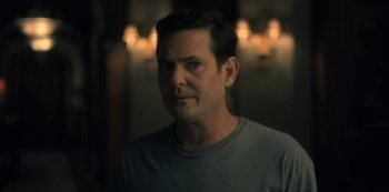 Movie still from “The Haunting of Hill House” (2018), directed by Mike Flanagan – A person wearing a gray t - shirt; Close Up shot, Over the shoulder angle