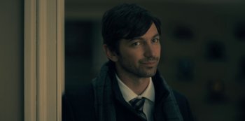 Movie still from “The Haunting of Hill House” (2018), directed by Mike Flanagan – A person wearing a suit and tie; Close Up shot, Over the shoulder angle