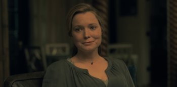 Movie still from “The Haunting of Hill House” (2018), directed by Mike Flanagan – A woman in a green shirt is smiling for the camera; Close Up shot, Over the shoulder angle