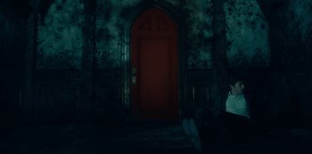A person sitting in front of a red door