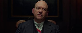 Movie still from “The Highwaymen” (2019), directed by John Lee Hancock – A man in a suit and tie sitting in a chair; Close Up shot, Low angle