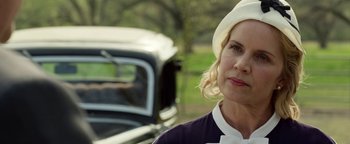 Movie still from “The Highwaymen” (2019), directed by John Lee Hancock – A woman wearing a hat standing in front of an old car; Close Up shot, Over the shoulder angle