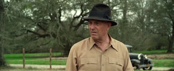 Movie still from “The Highwaymen” (2019), directed by John Lee Hancock – An older man wearing a black hat and a tan shirt; Close Up shot, Over the shoulder angle