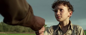 Movie still from “The Highwaymen” (2019), directed by John Lee Hancock – A young boy holding onto a leaf from an older man's hand; Close Up shot, Over the shoulder angle