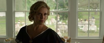 Movie still from “The Highwaymen” (2019), directed by John Lee Hancock – A woman standing in front of a window with people in the background; Close Up shot, Over the shoulder angle