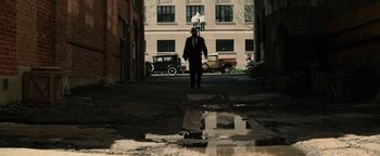 Movie still from “The Highwaymen” (2019), directed by John Lee Hancock – A man in a suit and hat walking down a street; Wide shot, Low angle