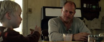 Movie still from “The Highwaymen” (2019), directed by John Lee Hancock – A man sitting at a table with a cup in front of him; Close Up shot, Over the shoulder angle