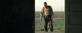 Movie still from “The Highwaymen” (2019), directed by John Lee Hancock – An old man standing in the middle of an open field; Medium shot, Low angle
