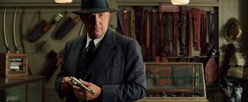 Movie still from “The Highwaymen” (2019), directed by John Lee Hancock – A man in a suit and hat holding a cell phone; Medium shot, Low angle