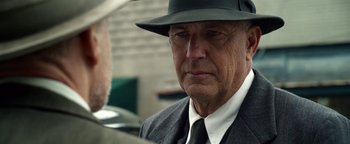 Movie still from “The Highwaymen” (2019), directed by John Lee Hancock – An older man wearing a suit and a hat; Close Up shot, Over the shoulder angle
