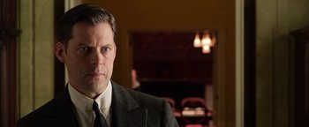 Movie still from “The Highwaymen” (2019), directed by John Lee Hancock – A man wearing a suit and tie in a room; Close Up shot, Over the shoulder angle