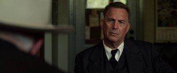 Movie still from “The Highwaymen” (2019), directed by John Lee Hancock – A person wearing a suit and tie; Close Up shot, Over the shoulder angle