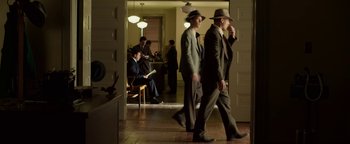 Movie still from “The Highwaymen” (2019), directed by John Lee Hancock – A group of men in suits and hats walking through a room; Wide shot, High angle