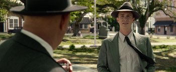 Movie still from “The Highwaymen” (2019), directed by John Lee Hancock – A man in a suit and a hat standing next to another man in a suit; Medium shot, Over the shoulder angle