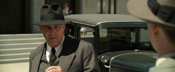 Movie still from “The Highwaymen” (2019), directed by John Lee Hancock – An older man wearing a suit and a hat standing in front of an old car; Close Up shot, Low angle