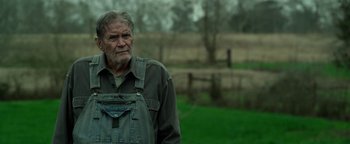 Movie still from “The Highwaymen” (2019), directed by John Lee Hancock – An older man standing in front of a field; Close Up shot, Over the shoulder angle