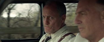 Movie still from “The Highwaymen” (2019), directed by John Lee Hancock – A person wearing a tie in a car; Close Up shot, Low angle