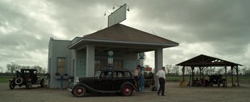 Movie still from “The Highwaymen” (2019), directed by John Lee Hancock – An old car is parked in front of a gas station; Extreme Wide shot, Low angle