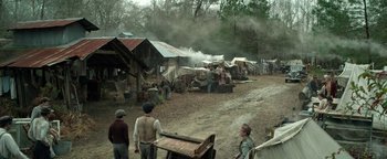 Movie still from “The Highwaymen” (2019), directed by John Lee Hancock – A group of people standing around a dirt road; Extreme Wide shot, High angle