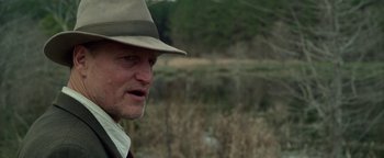 Movie still from “The Highwaymen” (2019), directed by John Lee Hancock – A person wearing a hat near a body of water; Close Up shot, Over the shoulder angle